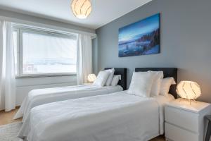 two white beds in a bedroom with a window at City Holiday Apartments 1 in Rovaniemi