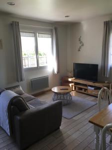 a living room with a couch and a flat screen tv at Chambre d'Hotes Les Hortensias in Rang-du-Fliers