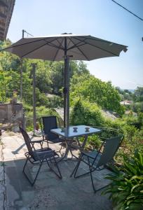 a table and chairs under an umbrella on a patio at Pelion house with stunning view to relax in Vyzitsa