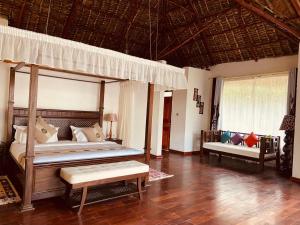 a bedroom with a canopy bed and a bench at Mara Sweet Acacia Lodge in Talek