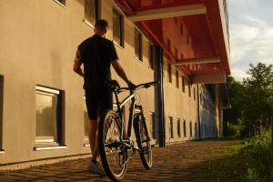 un hombre está de pie con su bicicleta fuera de un edificio en Rotel Inn en Passau