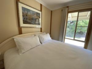1 dormitorio con 1 cama blanca grande y ventana en Ocean View walk to the beach & Surfers Point - Margaret River Properties, en Prevelly