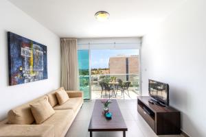 Una sala de estar con un sofá y un televisor. en Coralli Spa By Fig tree Bay, en Protaras
