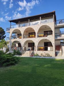 ein großes Backsteingebäude mit Balkonen und Rasen in der Unterkunft Aegialis Apartments (Dimitros) in Vourvourou