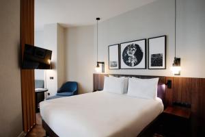 a hotel room with a white bed and a blue chair at Holiday Inn Telavi by IHG in Tʼelavi