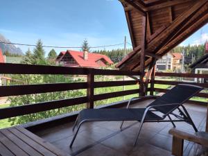 a chair on the balcony of a house with a view at Poiana dintre Brazi Chalet, Bucegi Panorama in Sinaia