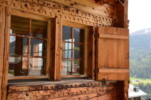 a window on the side of a wooden building with mountains at Vesmira in Sedrun