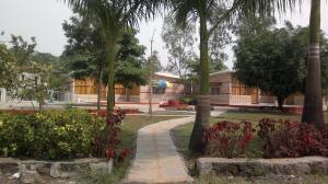 a garden with trees and a building in the background at Varenya Agro Resort in Kolvan