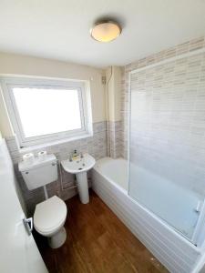 a bathroom with a toilet and a tub and a sink at Rayleigh Town Centre 3 Bedroom Apartment in Rayleigh