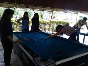 a group of people standing around a pool table at Varenya Agro Resort in Kolvan