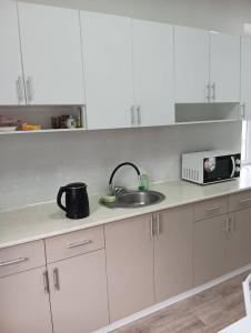 a white kitchen with a sink and a microwave at BekBro Hostel in Bishkek