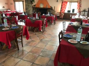 アルブスにあるAgriturismo Rocce Bianche - Bungalowsの赤いテーブルと椅子、暖炉のあるレストラン