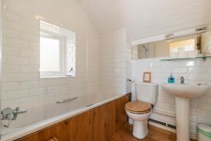 a bathroom with a tub and a toilet and a sink at The Nogg Cottages in Solva +71 photos