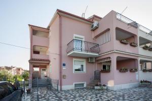 un bâtiment rose avec balcon dans une rue dans l'établissement Apartments Zaharija, à Rovinj