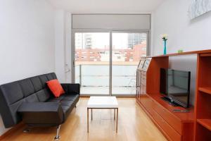 ein Wohnzimmer mit einem schwarzen Sofa und einem TV in der Unterkunft 1223 - POBLENOU APARTMENT in Barcelona