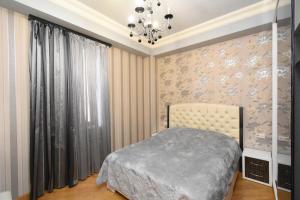 a bedroom with a bed and a chandelier at Ереван Уютная квартира в новостройке рядом с метро in Yerevan