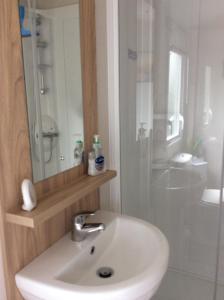 een badkamer met een witte wastafel en een douche bij Lake District Cumbria Gilcrux Solway Firth Cabin in Wigton