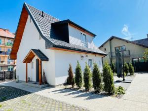 una casa blanca con árboles delante de ella en Dwie Sowy by Baltic Home, en Międzyzdroje