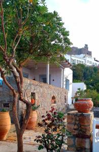 a tree in front of a house with large vases at Patmos Chora traditional villa Genadio in Patmos
