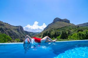 a woman laying on the edge of a pool in the water at Heated Private Ozone Salt Pool, Jacuzzi, Cinema, Ping Pong, Billiard, Ps5, Playground, Big Chess - Villa Rokka Luxe in Kissamos