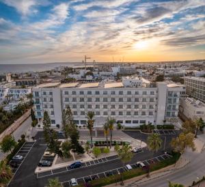 eine Luftansicht auf ein großes weißes Gebäude mit einem Parkplatz in der Unterkunft Nestor Hotel in Ayia Napa