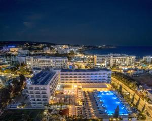 a building with a pool in front of the ocean at night at Nestor Hotel in Ayia Napa