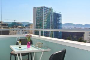 uma mesa com uma garrafa de vinho e flores numa varanda em Chiara Lovely Apartment em Tirana