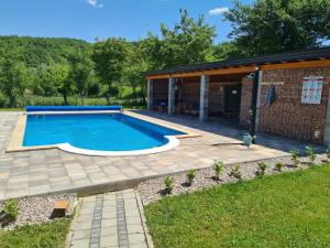 a swimming pool with a patio and a house at Oasis of peace in Bihać