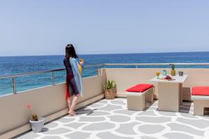 Una mujer parada en un balcón con vistas al océano en Almyra Apartments & Suites, en Sfakaki