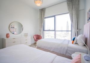 - une chambre avec 2 lits, un miroir et une fenêtre dans l'établissement Nasma Luxury Stays - Bellevue Tower 1, à Dubaï