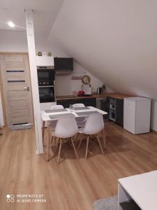 a kitchen and dining room with a table and chairs at Apartament u Małgosi in Kołczewo