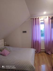 Schlafzimmer mit einem Bett mit lila Vorhängen und einem Fenster in der Unterkunft Apartament u Małgosi in Kołczewo