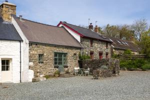 una vieja casa de piedra con una mesa delante en The Nogg Cottages en Solva