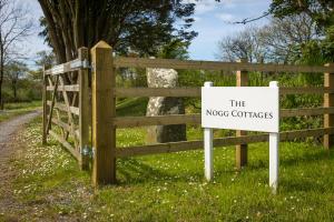 a wooden fence with a sign that reads the nocos contracts at The Nogg Cottages in Solva