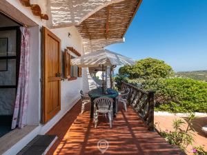 un tavolo e sedie su un balcone con ombrellone di House Eleonora - Villaggio Polifemo a Cala Sapone
