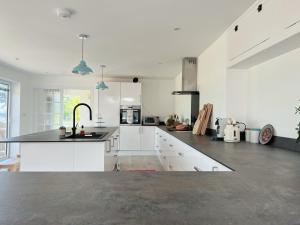 a kitchen with white cabinets and a black counter top at Shan Mu Inn Deluxe Hot-tub seaview apartment in Newlyn