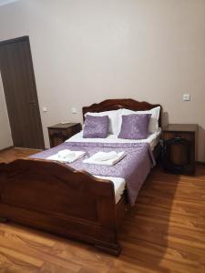 sypialnia z dużym drewnianym łóżkiem z fioletowymi poduszkami w obiekcie Beehives w Kutaisi