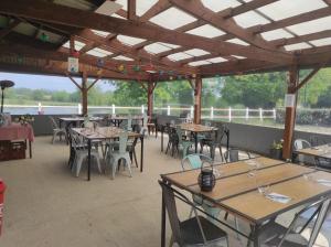 a restaurant with wooden tables and chairs and a roof at le hangar 87 in Bussière-Portevine