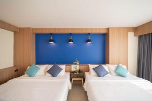 two beds in a room with a blue wall at The Sixteenth Naiyang Beach Hotel SHA Plus in Nai Yang Beach +37 photos