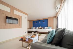 a living room with a couch and a tv at The Sixteenth Naiyang Beach Hotel SHA Plus in Nai Yang Beach