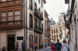 un grupo de personas caminando por una calle con edificios en Pension Iberia, en Llanes