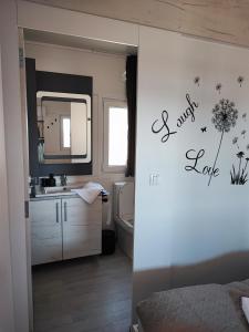 ein Badezimmer mit einem Waschbecken, einem WC und einem Spiegel in der Unterkunft Hollers Holiday Homes Haus Max in Drage