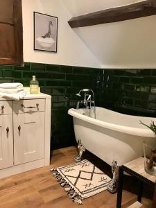 a bathroom with a bath tub and a green wall at Dunster Luxe Nook in Dunster