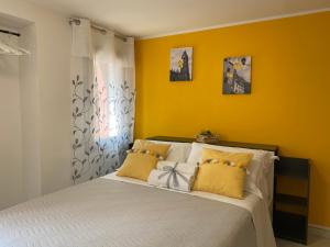 1 dormitorio con paredes amarillas y 1 cama con almohadas amarillas en LAGUNA BLU Camera SOLE con terrazza panoramica in comune, en Chioggia