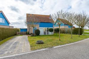 a blue house with trees in the front yard at Antibes 232 - Kustpark Village Scaldia in Hoofdplaat