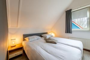 a bedroom with a white bed with a window at Antibes 232 - Kustpark Village Scaldia in Hoofdplaat