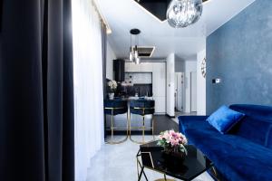 a living room with a blue couch and a kitchen at Resort Apartamenty Klifowa Rewal 80 in Rewal