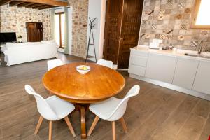 cocina y comedor con mesa de madera y sillas blancas en Casa Portelles en Dénia