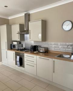 a kitchen with white cabinets and a clock on the wall at Harlow Coach House in Harrogate