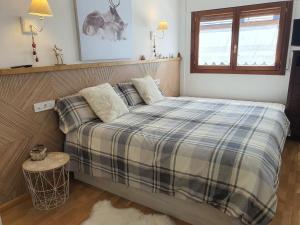 1 dormitorio con 1 cama con manta a cuadros en ES CÒVES en Vielha